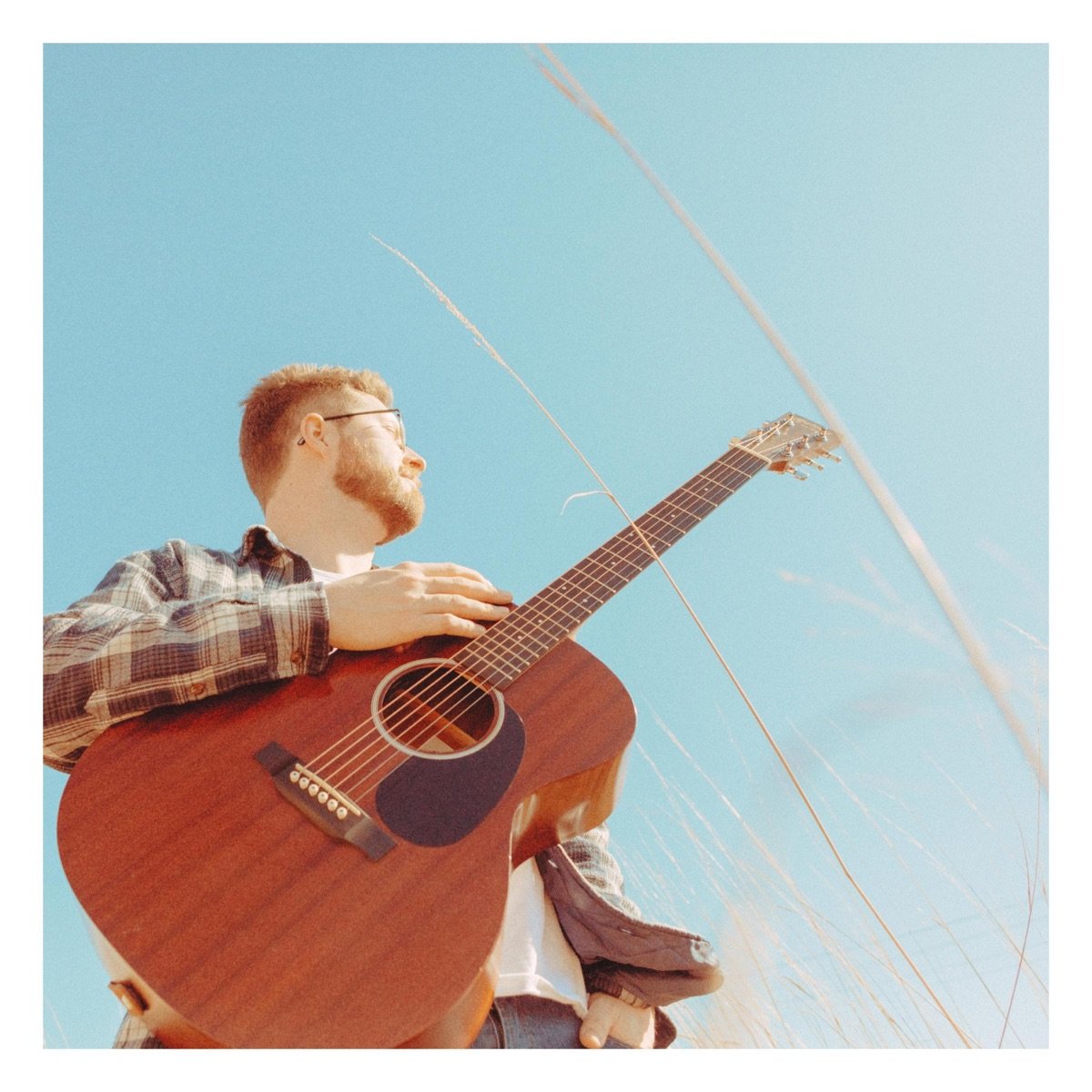 Matt Rees standing outdoors with an acoustic guitar