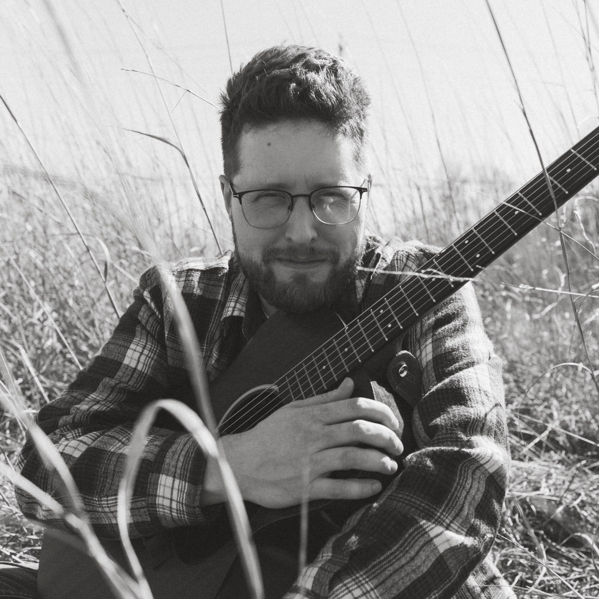 Matt Rees seated outdoors with an acoustic guitar