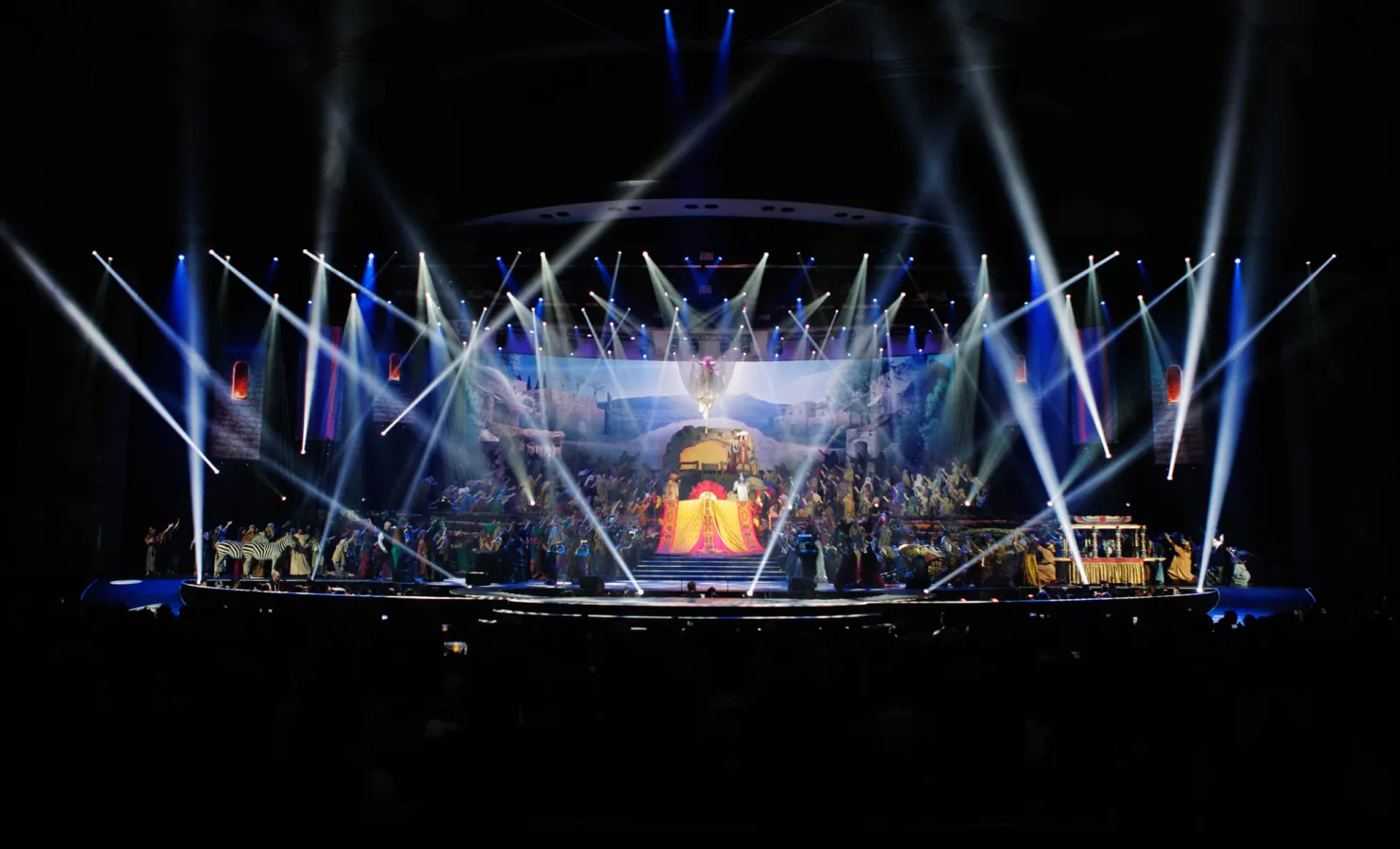 A wide view of The Gift of Christmas stage with performers and sweeping lights