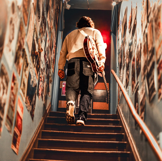 Tyler Philip Ratcliffe walking upstairs with a guitar
